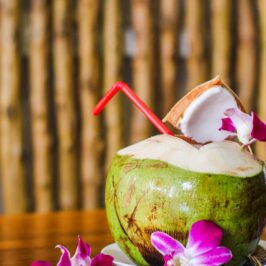 Fresh Coconut Juice with Pink Flowers on a Wooden Table